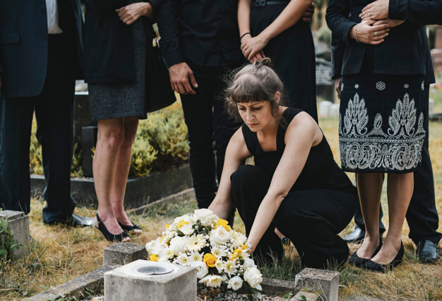 ผู้หญิงวางดอกไม้หน้าหลุมศพ